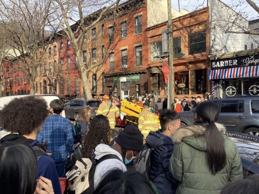 Firefighters rush into Brooklyn Tech with stretchers as students look on. 