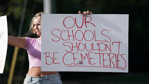 Student Gretchen Gierlach, 18, holds up signs following a shooting at Apalachee High School in Winder, Georgia. 
